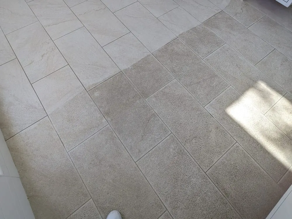 A tile floor half cleaned: the clean section on the upper left is visibly lighter than the soiled section
