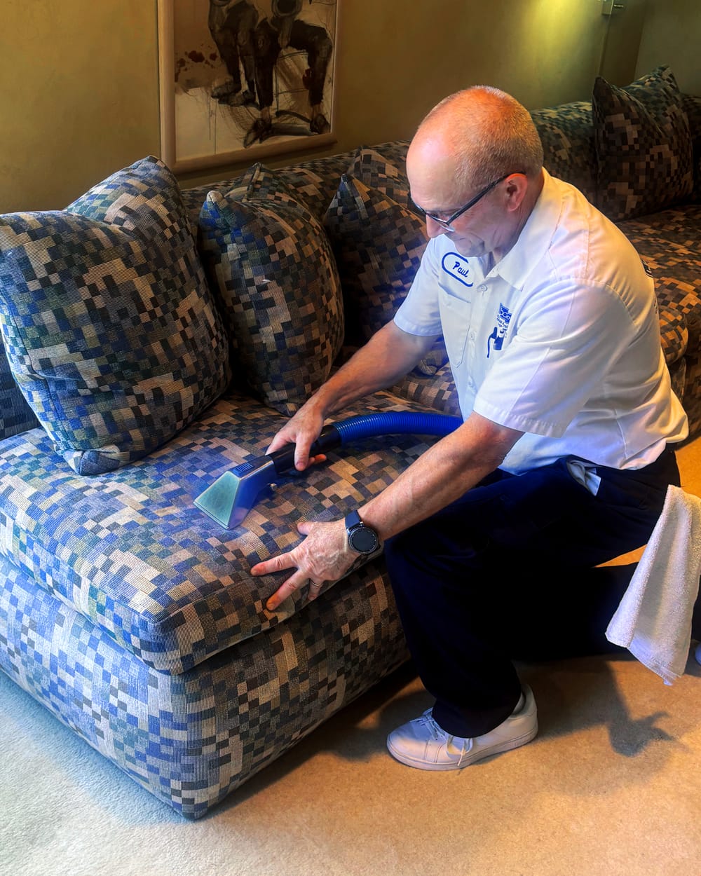Burrous Brothers Company technician cleaning an upholstered chair with a hand tool